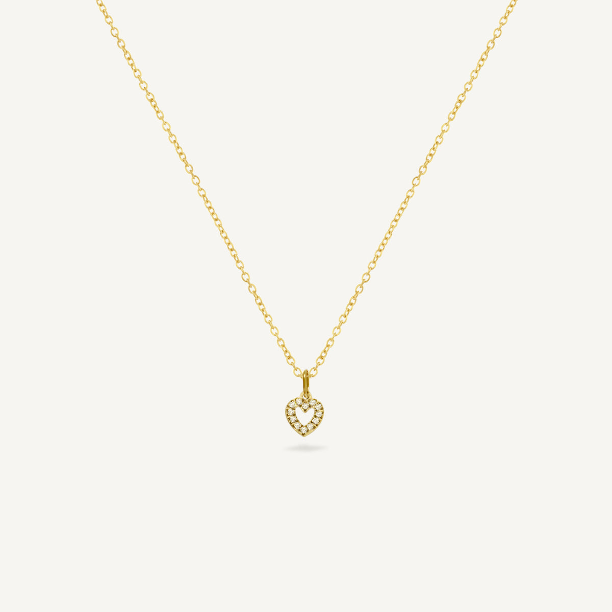 Gold necklace with a heart-shaped pendant on a white background